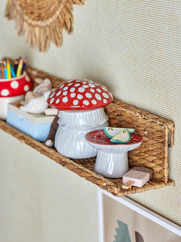 A shelf hanging on a wall with mushroom decor on it. The mushroom decor consists of a jar, a pencil holder and a piedestal bowl. 