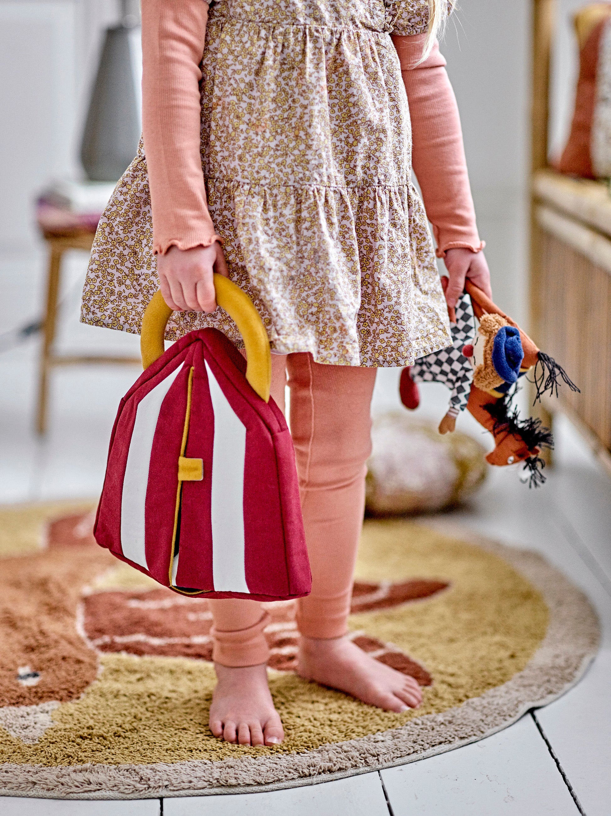 Little girl holding a plush circus tent in one hand and a clown and a horse in the other